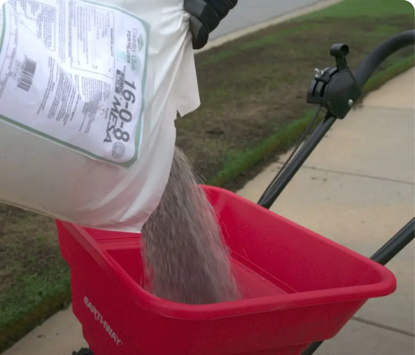 pouring fertilizer into spreader
